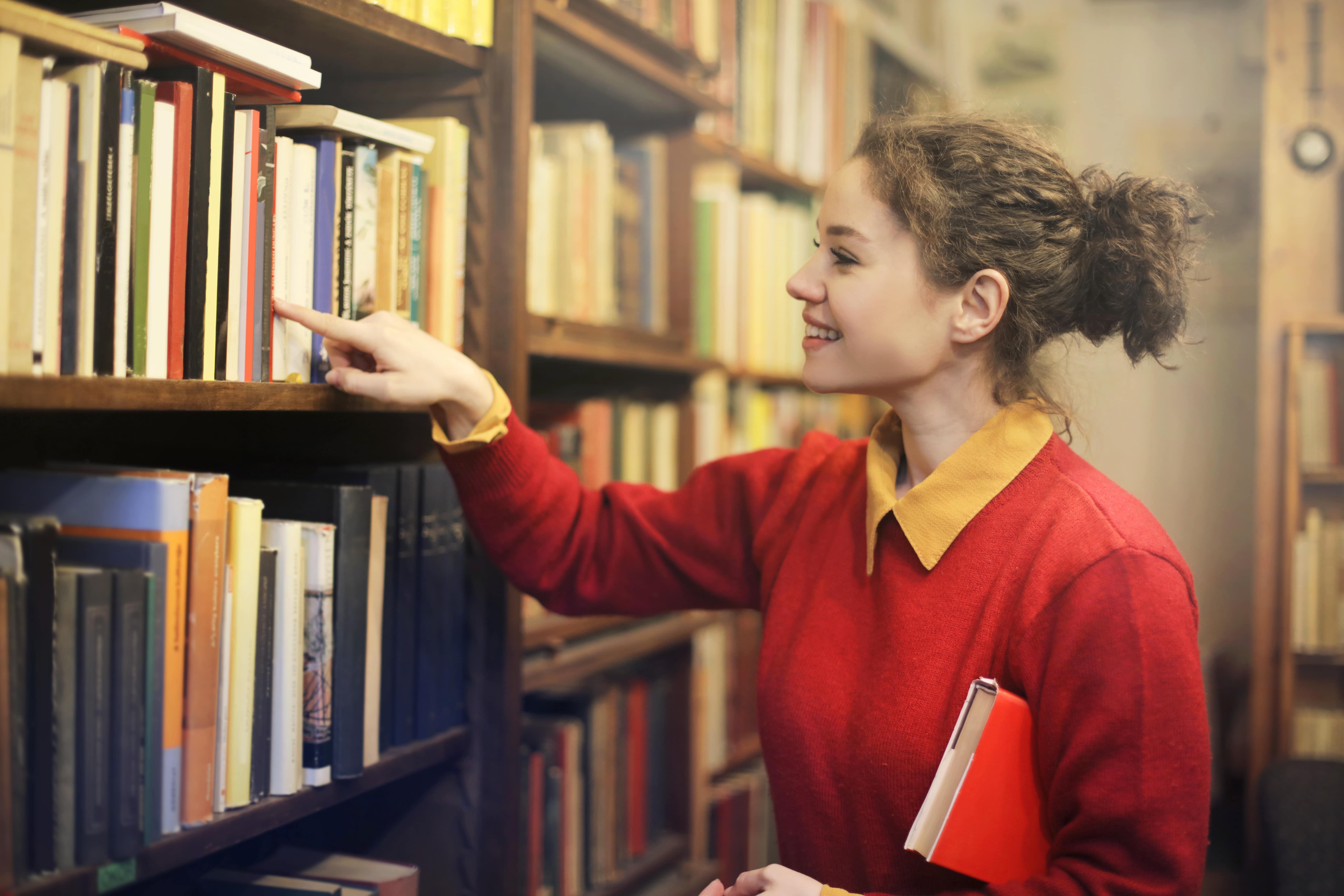 jovem procurando um livro na biblioteca